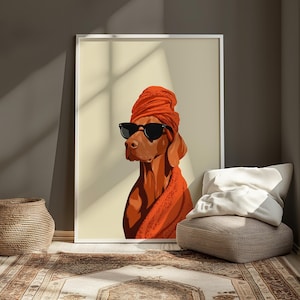 May include: A framed art print of a Vizsla dog wearing a turban and sunglasses. The dog is rendered in shades of brown and orange, with a black frame. The artwork is displayed in a room with a neutral colour palette.