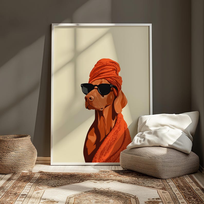 May include: A framed art print of a Vizsla dog wearing a turban and sunglasses. The dog is rendered in shades of brown and orange, with a black frame. The artwork is displayed in a room with a neutral colour palette.