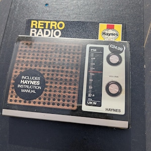 May include: A retro-style radio in its original packaging. The radio has a brown speaker grill and a white control panel with a tuning dial and volume knob. The packaging includes the text "Retro Radio" and "Haynes".