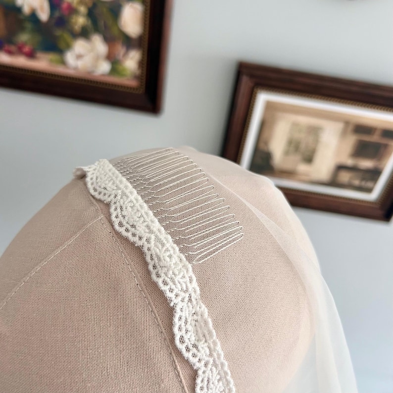 May include: A bridal veil with a delicate, scalloped lace trim and a comb for secure placement in the hair. The veil is a soft white color, and the lace trim adds a touch of elegance. The comb is silver.