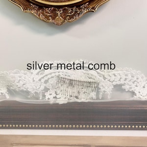 May include: A bridal veil with a silver metal comb. The veil is white and has a delicate lace trim. The comb is made of silver metal and is attached to the veil. The text "silver metal comb" is displayed on the image.