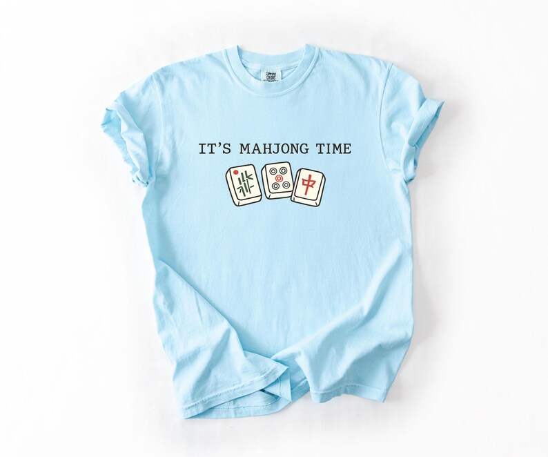 A light blue t-shirt with the text "IT'S MAHJONG TIME" printed on it, along with a graphic of a mahjong tile.