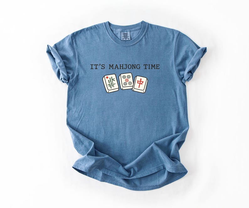 A blue t-shirt with the text "IT'S MAJONG TIME" printed on it, along with a graphic of a mahjong tile.