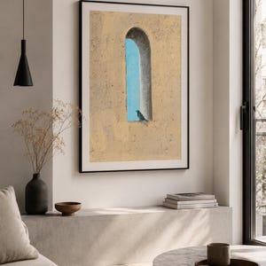 May include: A framed wall art print featuring a textured beige wall with a tall, arched window opening. A bright blue sky is visible through the arch, and a small dark bird is perched on the lower ledge of the window frame in the centre.