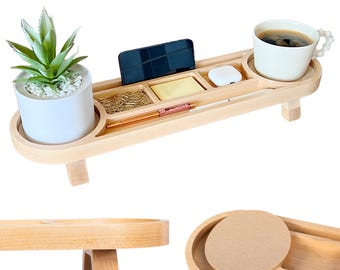 May include: A light-coloured wooden desk organiser with a built-in plant holder, compartments for office supplies, and a cup holder. The organiser holds a small plant, a smartphone, a pen, and a cup of coffee. The organiser is supported by two small legs.