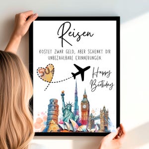 May include: A framed print with the German word "Reisen" at the top, meaning "travel". The print features a black airplane, a heart with "50" inside, and famous landmarks. The text "Happy Birthday" is also included.