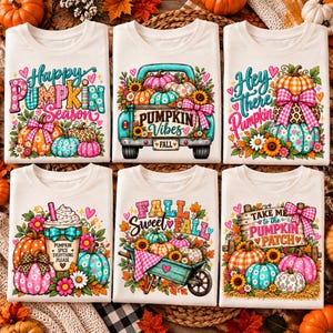May include: Six white t-shirts featuring colorful fall-themed graphic prints. Designs include pumpkins, a teal truck, a coffee cup with the text Pumpkin Spice Everything Please, a wheelbarrow, and a sign reading Take Me to the Pumpkin Patch.