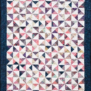 May include: A rectangular quilt featuring a repeating pattern of half-square triangles in shades of pink, purple, and dark blue, interspersed with white fabric triangles. The quilt is finished with a dark blue border with a swirling pattern.