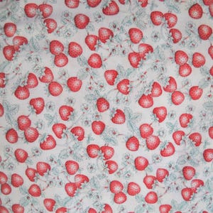 K&ouml;nnte beinhalten: Ein wei&szlig;er Stoff mit einem sich wiederholenden Muster aus roten Erdbeeren und gr&uuml;nen Bl&auml;ttern.