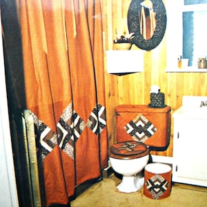 May include: A vintage bathroom set featuring a rust-colored shower curtain and matching toilet seat cover, tank cover, and wastebasket. The set has a geometric diamond pattern in black, white, and brown. A black oval mirror hangs above a white shelf.