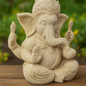 May include: A beige-colored statue of the Hindu deity Ganesha, seated in a meditative pose. The sculpture features intricate details, including a crown, large ears, and multiple arms holding various objects. The statue is placed on a wooden surface.