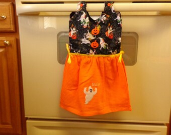 Peut inclure: Serviette de cuisine d'Halloween orange et noire avec un fantôme et le mot "Boo!" brodé dessus. La serviette a un imprimé noir et blanc de fantômes, de citrouilles et de maïs sucré.