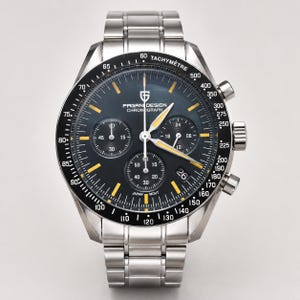 Peut inclure: Une montre chronographe Pagani Design en acier inoxydable avec un cadran noir, des accents jaunes et une lunette tachymétrique. La montre comporte trois sous-cadrans et un affichage de la date. Le bracelet est en acier inoxydable.