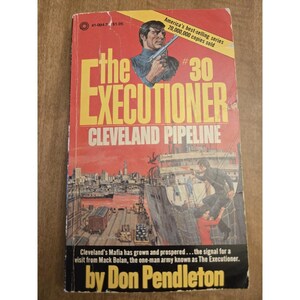 May include: Vintage paperback book titled "The Executioner: Cleveland Pipeline" by Don Pendleton. The cover features a man holding a gun, a harbor scene, and the text "America's best-selling series 20,000,000 copies sold."