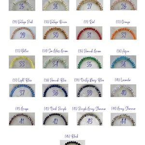 May include: A collection of twenty-one beaded bracelets arranged in a grid, each labeled with a number from 25 to 45 and a color name. The bracelets feature faceted crystal beads in various colors including clear, ivory, champagne, pink, red, orange, yellow, green, blue, purple, gray, and black.