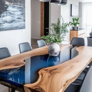 Puede incluir: Una mesa de comedor moderna con una tapa de madera de borde vivo y un río de resina epoxi azul. La mesa está sostenida por patas de metal negro y rodeada de sillas grises. Un jarrón decorativo está sobre la mesa.