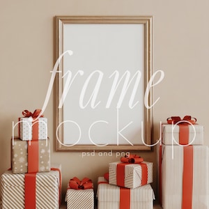 May include: A gold framed mockup with a blank white space, surrounded by wrapped gifts. The gifts are in various sizes and patterns, including stripes and snowflakes, tied with red ribbons. The background is a neutral beige.