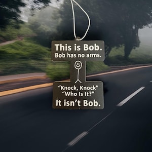 May include: Black rectangular air freshener with a white string, featuring the text "This is Bob. Bob has no arms." Below is a stick figure and the text "Knock, Knock, Who is it? It isn't Bob."