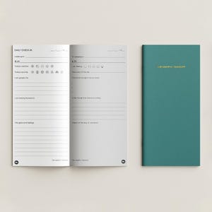 May include: A teal journal titled THE MINDFUL TRAVELER in gold foil on the cover, displayed next to its open interior pages. The pages feature a Daily Check-In layout with prompts for weather, journey, gratitude, feelings, and daily sketches.