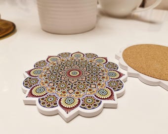 May include: A decorative coaster with a detailed mandala design in shades of red, yellow, blue, and green. The coaster has a white, scalloped edge. A second coaster with a cork surface is also visible.