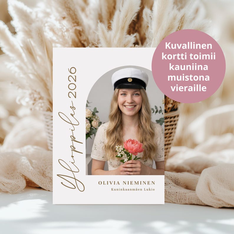 May include: A graduation announcement card with a photo of a smiling person wearing a white cap and holding a pink flower. The card has text in gold, including the year 2026 and a name. A pink circle with text is in the upper right.