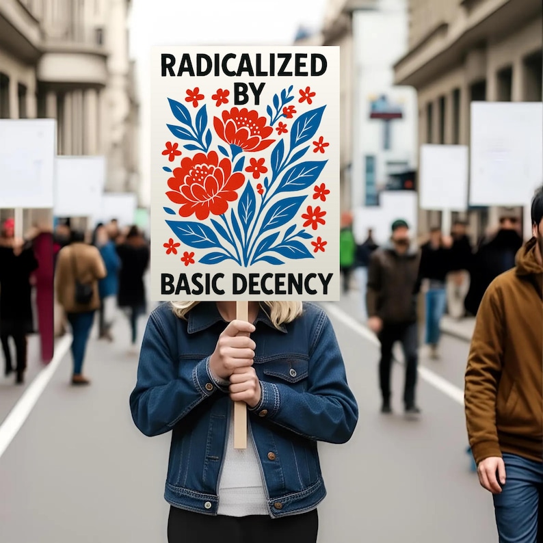 Puede incluir: Una persona sostiene un cartel con las palabras "RADICALIZED BY BASIC DECENCY" en texto negro. El cartel presenta un dise&ntilde;o floral con flores rojas, hojas azules y acentos de estrellas rojas. La persona lleva una chaqueta vaquera azul.