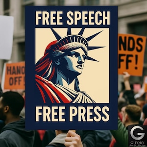 Op de afbeelding: Een bord dat in een menigte wordt omhooggehouden met de woorden "FREE SPEECH" en "FREE PRESS" in witte letters. Het bord toont een illustratie van het Vrijheidsbeeld in blauw, rood en crème.