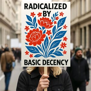 Puede incluir: Un cartel con las palabras "RADICALIZED BY BASIC DECENCY" en negro. El cartel presenta un dise&ntilde;o floral con flores rojas y hojas azules. El fondo es una escena callejera borrosa.