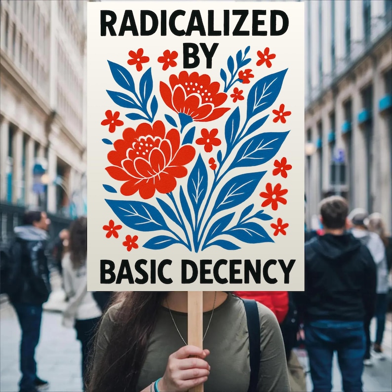 Puede incluir: Un cartel con las palabras "RADICALIZED BY BASIC DECENCY" en texto negro, sostenido por una persona. El cartel presenta un dise&ntilde;o floral con flores rojas y hojas azules. El fondo muestra una escena callejera con gente.