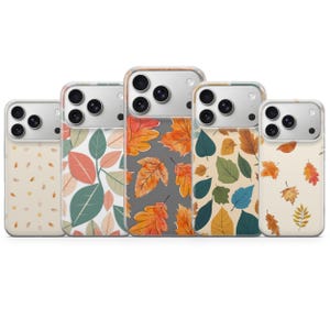 May include: Five clear smartphone cases arranged in a row, each featuring a distinct autumn-themed pattern. The designs include various arrangements of watercolor-style leaves in shades of orange, yellow, green, and brown against different backgrounds.