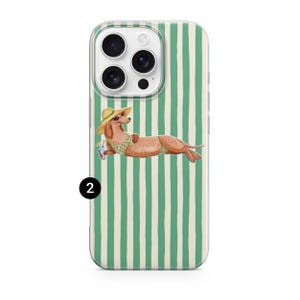 May include: A clear phone case with a green and white striped design. The case features a watercolour illustration of a dachshund wearing a sun hat and swimsuit, holding a drink. The dog is lounging on the case.