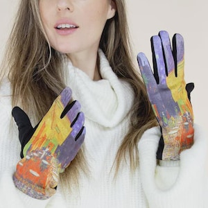 May include: Gloves featuring a vibrant, abstract cityscape design on the back of the hands. The gloves have black palms and cuffs. The person in the image is wearing a white turtleneck sweater.