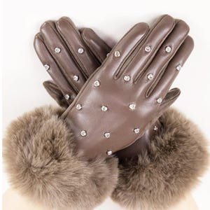 Könnte beinhalten: Braune Lederhandschuhe mit Strasssteinen. Die Handschuhe haben eine Pelzmanschette. Die Handschuhe sind neutral gefärbt und für kaltes Wetter geeignet.