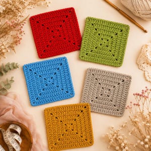 May include: Five colorful, square crochet coasters in red, green, blue, gray, and yellow. Each coaster features a central design and a textured surface. The coasters are arranged on a light-colored surface with yarn and crochet hook in the background.
