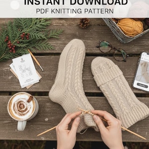 Puede incluir: Una escena acogedora con un par de calcetines y un mitón tejidos con hilo beige, con agujas de tejer en uso. La imagen incluye una taza de café, lana y el texto "INSTANT DOWNLOAD PDF KNITTING PATTERN".
