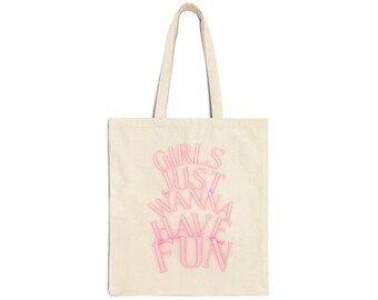 May include: Cream-colored tote bag with the phrase "GIRLS JUST WANNA HAVE FUN" in pink, stylized lettering. The bag has matching cream-colored handles and is made of a sturdy fabric, suitable for carrying various items.