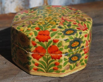 May include: A yellow octagonal box with a floral design. The box is decorated with red, yellow, green, and blue flowers.