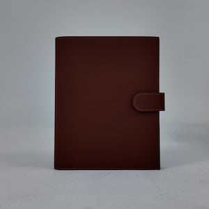 Peut inclure: Un journal en cuir marron au design simple. Le journal a une forme rectangulaire avec des coins arrondis et une fermeture &agrave; rabat. La couverture est d'une couleur marron riche et unie, et la fermeture est une languette en cuir marron assortie.