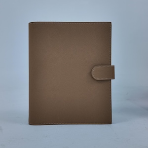 Peut inclure: Un agenda rectangulaire de couleur beige avec une fermeture &agrave; languette incurv&eacute;e. L'agenda est fait d'un mat&eacute;riau lisse et a une bordure cousue. La couverture est de couleur unie et neutre, adapt&eacute;e &agrave; divers usages.