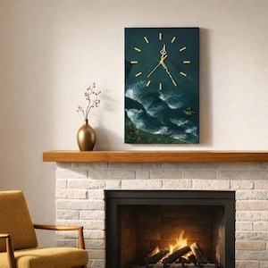 Puede incluir: Reloj de pared rectangular con una escena de océano azul oscuro y manecillas e indicadores dorados. El reloj está montado sobre una chimenea con una repisa de madera. Un jarrón dorado con flores secas descansa sobre la repisa.
