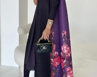 May include: A black pleated long coat with a purple floral design on the back. The coat is paired with white pants and clear heels. A small black handbag with a gold chain is held in the hand.