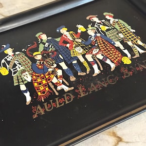 May include: Black rectangular serving tray featuring a colourful illustration of Scottish men in kilts. The men are in a line, some holding drinks. The words "Auld Lang Syne" are printed in gold lettering.