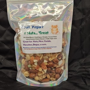 Może przedstawiać: Przezroczysta, holograficzna torba wypełniona mieszanką orzechów, suszonych owoców i kropelek jogurtu. Etykieta głosi "Fruit, Yogurt & Nuts... Treat" z myszą z kreskówki. Przysmak jest dla małych zwierząt.