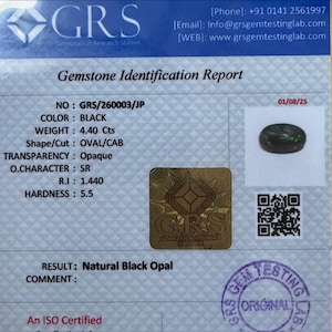 May include: A gemstone identification report from GRS. The report details a black oval-cut opal weighing 4.40 carats. The report includes the stone's transparency, optical character, refractive index, and hardness. The report is dated 01/08/25.