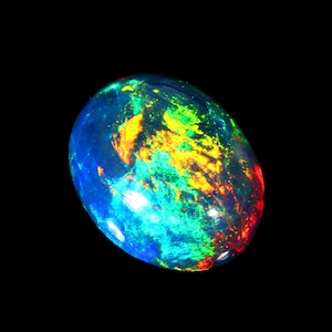 Könnte beinhalten: Ein ovales, schillerndes Opal-Edelstein. Der Stein zeigt eine lebendige Farbpalette, darunter Blau, Grün, Gelb und Rot, vor einem dunklen Hintergrund. Die Oberfläche des Opals hat ein poliertes, glattes Aussehen und zeigt sein inneres Farbspiel.