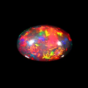 Könnte beinhalten: Ein ovaler Opal-Edelstein vor schwarzem Hintergrund. Der Opal zeigt eine schillernde Farbpalette, darunter Rot, Gelb, Grün und Blau, wodurch ein feuriger, schillernder Effekt entsteht. Der Edelstein ist poliert und glatt.