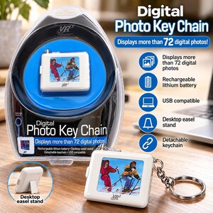 May include: A white digital photo keychain with a screen displaying two skiers. The device features a rechargeable lithium battery, USB compatibility, a detachable keychain, and a desktop easel stand. It is packaged in a clear plastic blister pack.