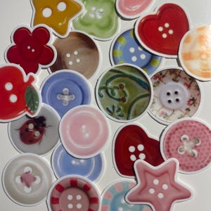 May include: A collection of colorful, decorative buttons in various shapes, including stars, hearts, and flowers. The buttons feature a variety of colors and patterns, such as red, pink, blue, and green, with visible buttonholes.