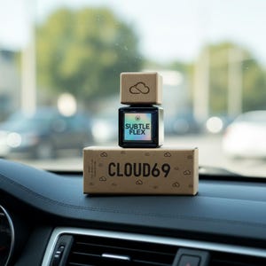 May include: A wooden-topped, black square bottle with the text "SUBTLE FLEX" and a box with the text "CLOUD69" on a car dashboard. The bottle has a cloud logo on the wooden top. The box is brown with cloud graphics.
