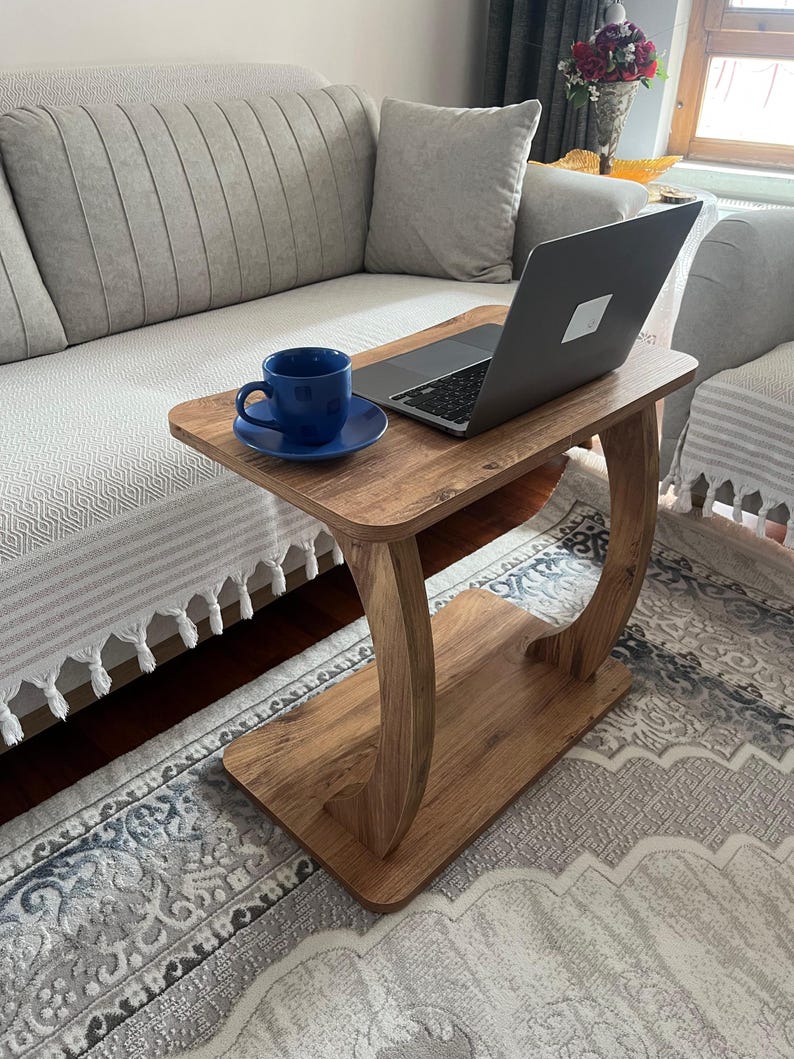 Puede incluir: Una mesa auxiliar de madera con un port&aacute;til y una taza y un platillo azules. La mesa tiene un acabado de veta de madera marr&oacute;n claro y un dise&ntilde;o de patas curvas. La mesa mide 61 cm de largo, 30 cm de ancho y 61 cm de alto.